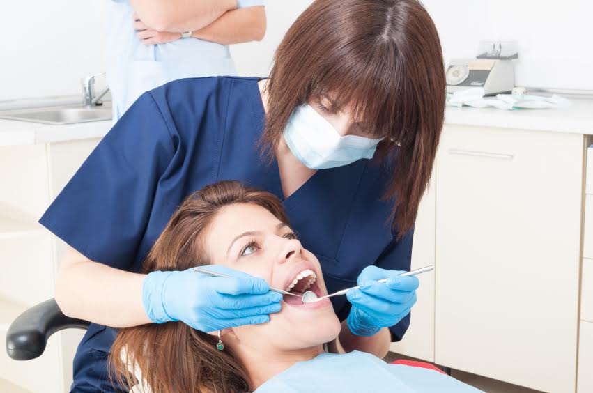 Oral hygienist or orthodontist at work on a female patient with beautiful teeth