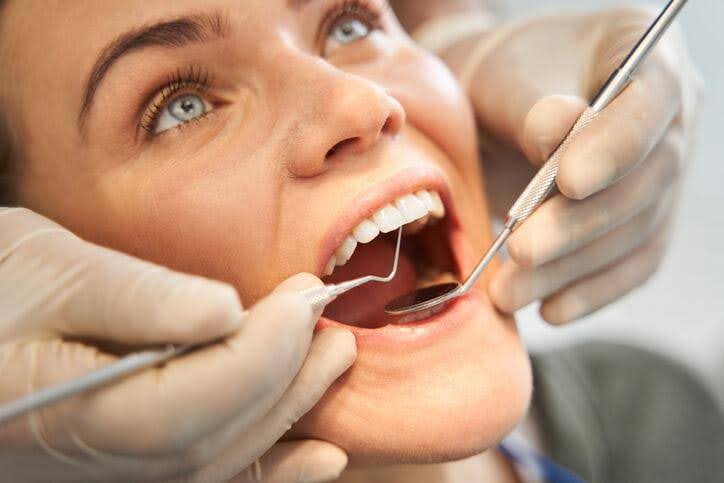 A close-up of a Dental Hygienist performing a dental cleaning on a female patient