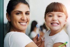 A mother and young child brushing teeth together, emphasizing early oral care linked to oral embryology and histology.