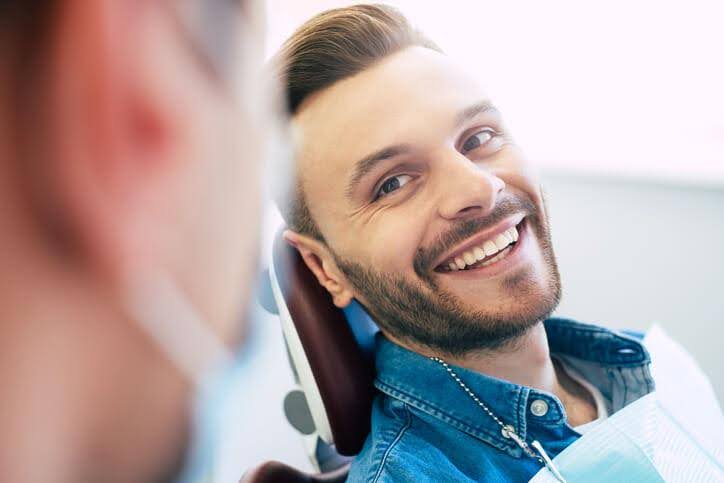 A patient smiling in a dental chair after a consultation, a common scenario covered in dental hygienist training.