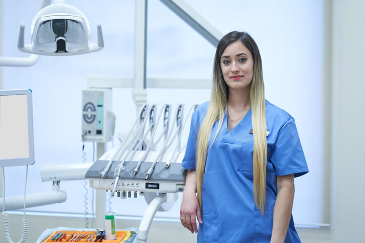Woman pursuing a dental hygienist career standing in a dental office