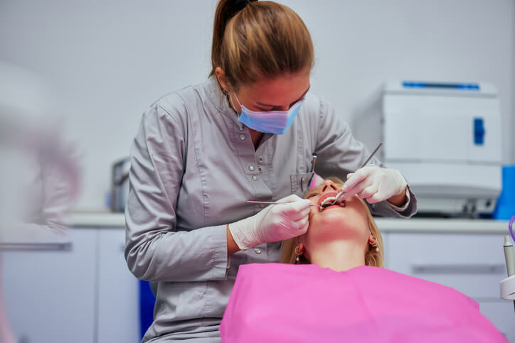 Dental hygienist removing plaque from patient’s teeth