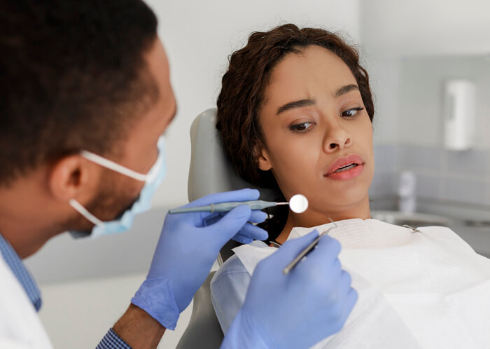 A nervous woman at a dentist appointment as addressed in dental hygiene training.
