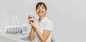 A dental hygienist training grad posing while holding a model of the mouth