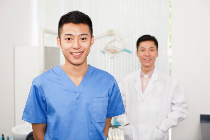 dental assistant school grad posing with a dentist in a clinic