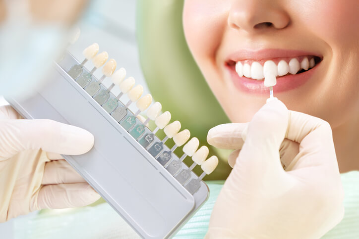 A dental hygienist training grad colour matching for a tooth whitening