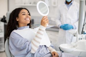 A dental hygienist training grad showing a patient the results of their tooth whitening