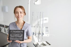 A dental hygiene diploma holder posing in a clinic with a digital X-ray