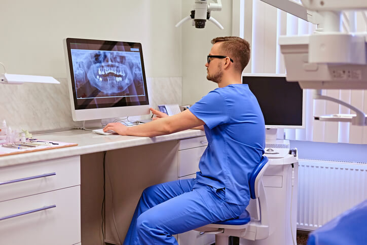 A dental hygienist looking at tooth x-ray photos obtained through teledentistry