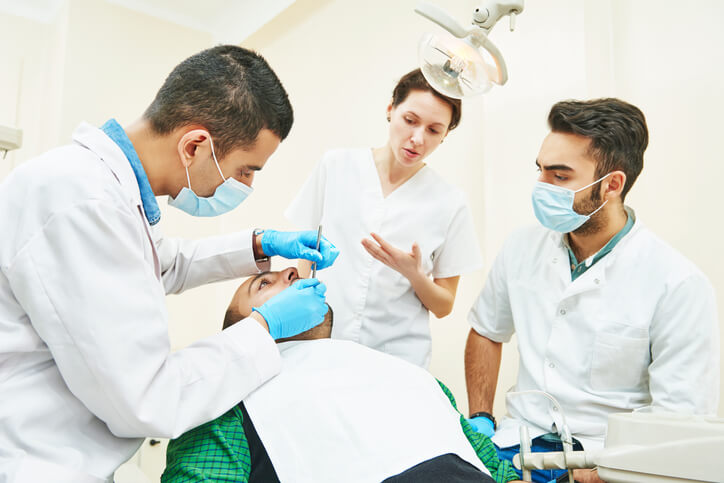 An instructor guiding students through a hands-on dental procedure