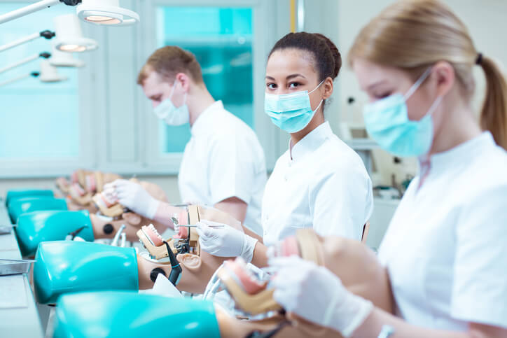 A row of students in a dental assistant diploma program learning chairside procedures, answering part of the question, What is a dental assistant