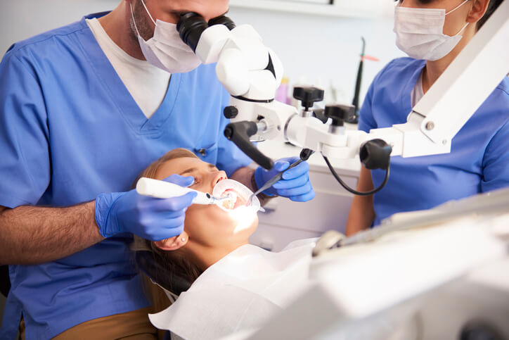 A dental assistant supporting a dentist during a patient procedure, answering part of the question, What is a dental assistant