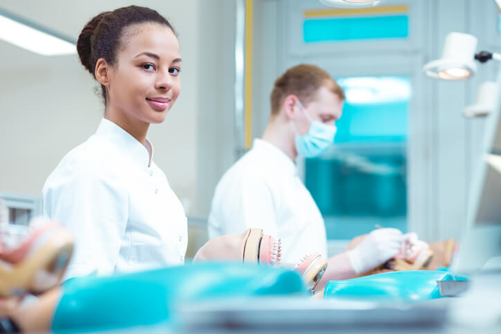 A student learning practical dental assistant skills in a classroom setting