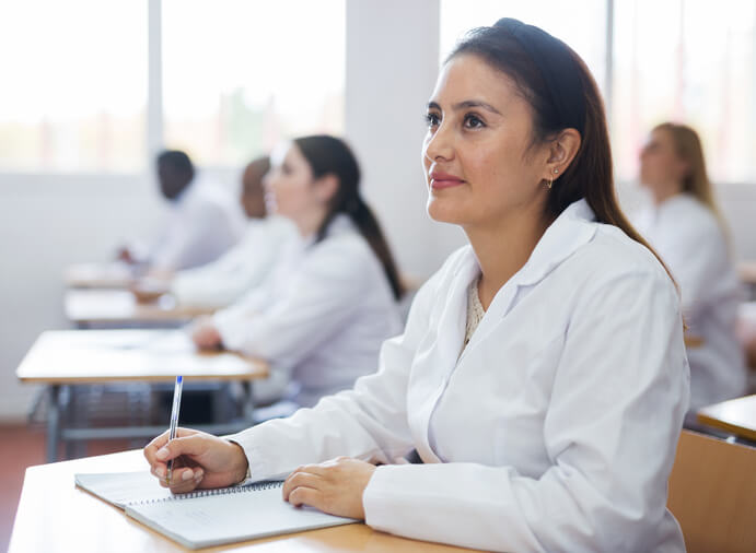 A dental hygiene student taking notes in a classroom