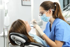 Dental hygiene professional performing an oral examination and preventive care for a patient during a routine dental hygiene appointment.