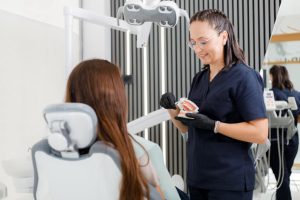 A dental assistant explains oral care to a patient in a dental office, illustrating the patient-facing support common in dental assisting.