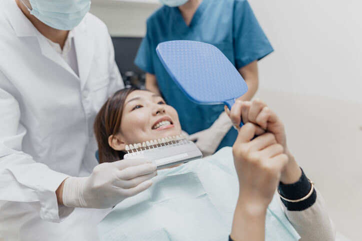 A dental assistant supporting a dentist during a patient exam in a dental clinic