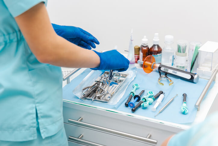 A dental assistant preparing surgical instruments in an oral surgery clinic