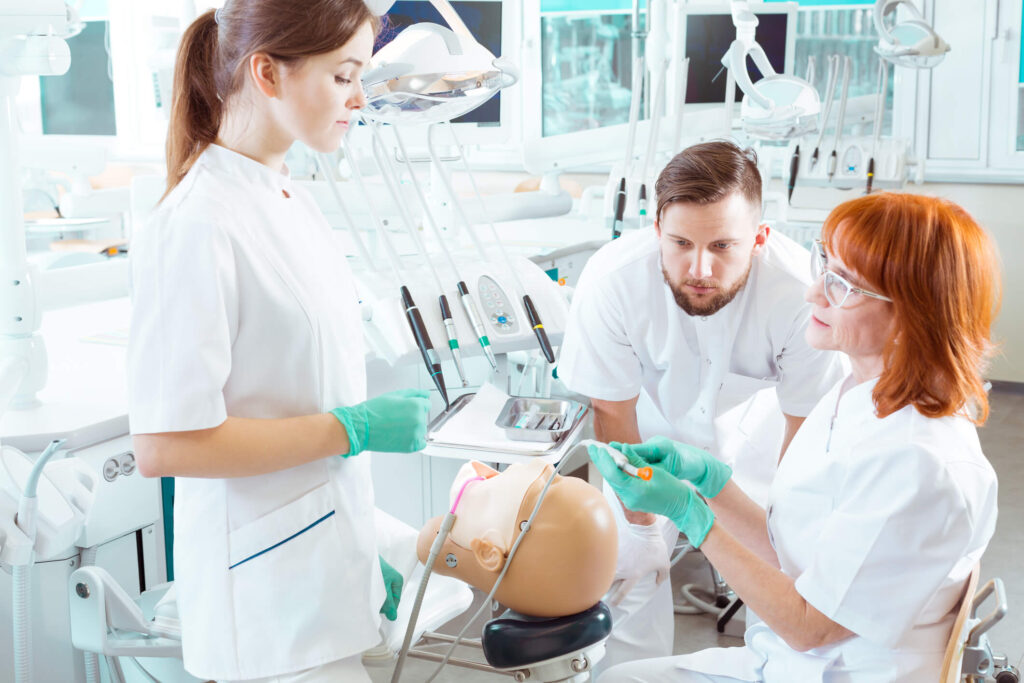 Instructor guiding students through hands-on dental hygienist training