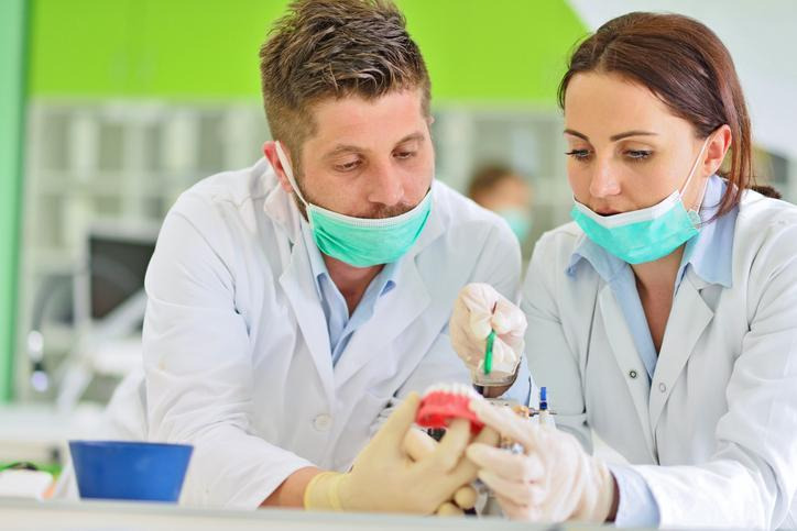 Instructor guiding a student during hands-on dental hygiene training